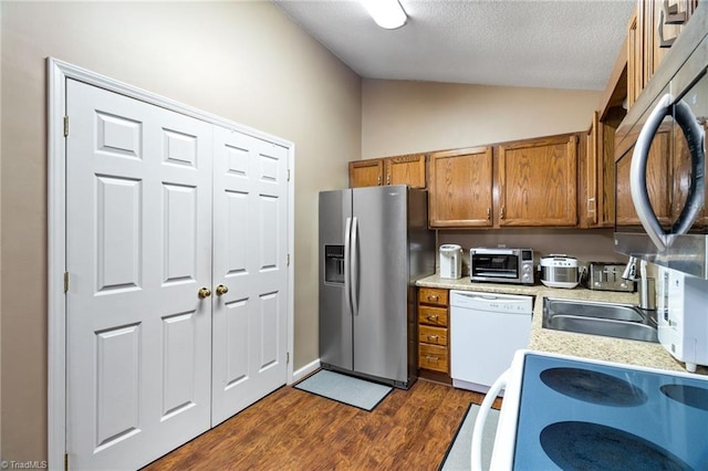 516 John St, Eden, NC 27288 - kitchen featuring brown cabinets, stainless steel appliances, lofted ceiling, light countertops, and dark wood-type flooring
