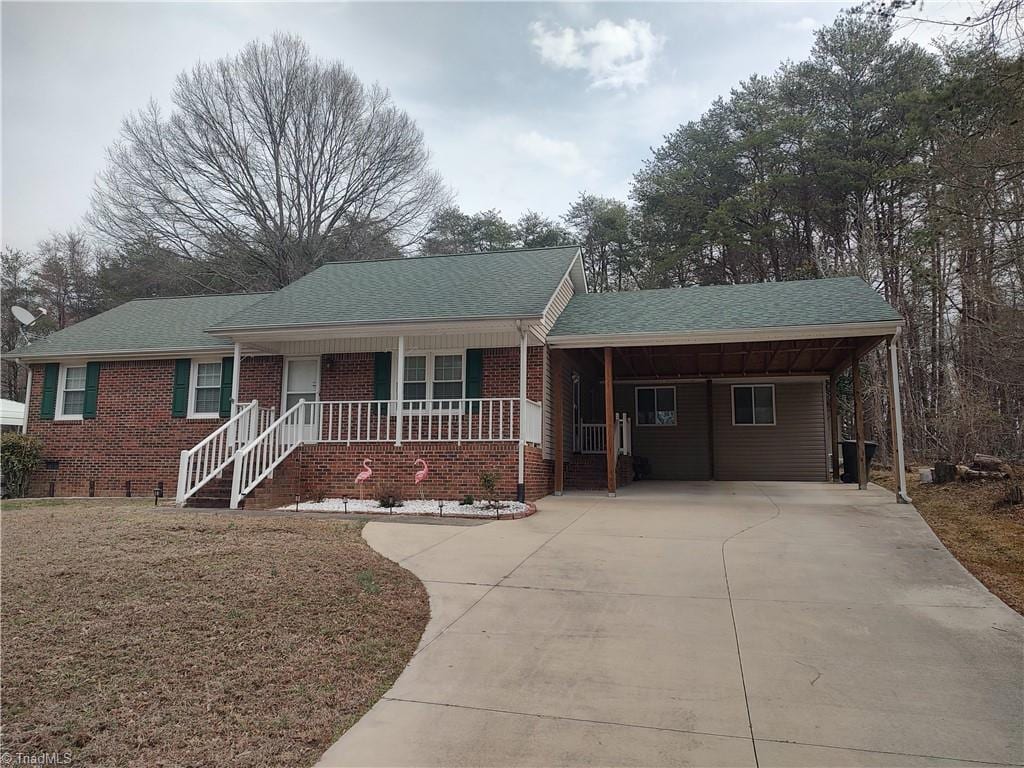 single story home featuring concrete driveway, a porch, crawl space, a front lawn, and brick siding