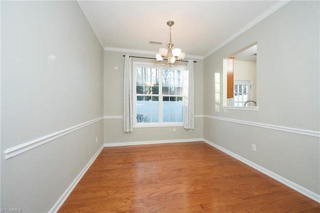 unfurnished dining area featuring hardwood / wood-style floors, crown molding, and a chandelier