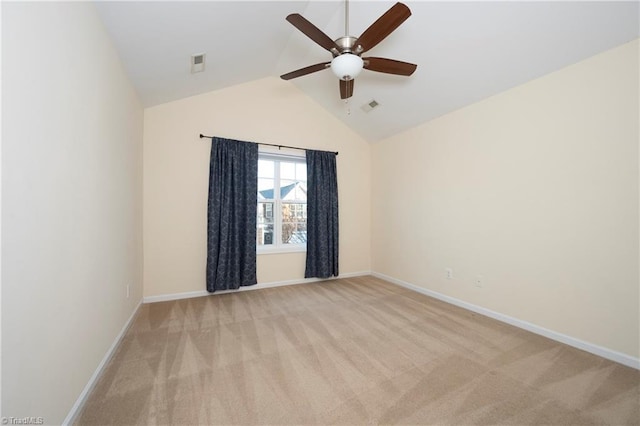 empty room featuring ceiling fan, vaulted ceiling, and light colored carpet