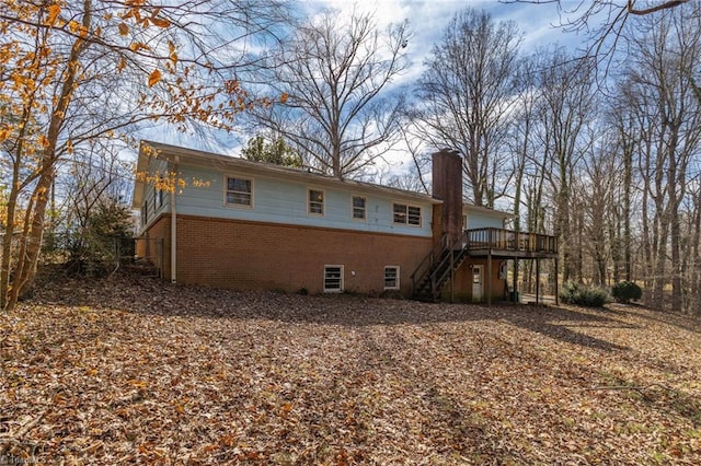 rear view of house with brick siding, stairway, a chimney, and a wooden deck