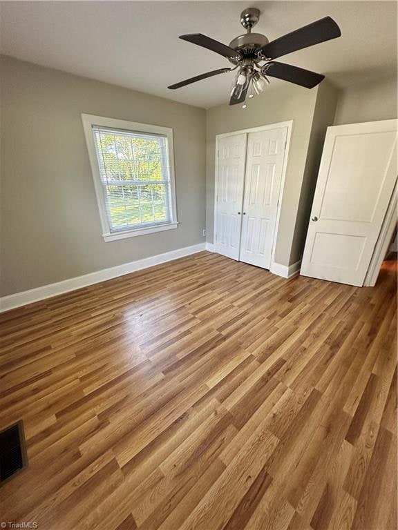 unfurnished bedroom featuring hardwood / wood-style floors, ceiling fan, and a closet