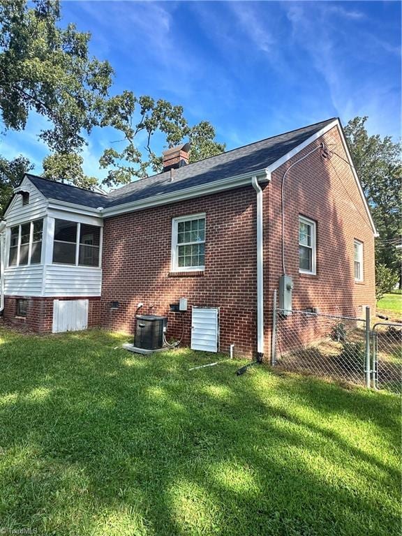 back of property with a sunroom and a lawn