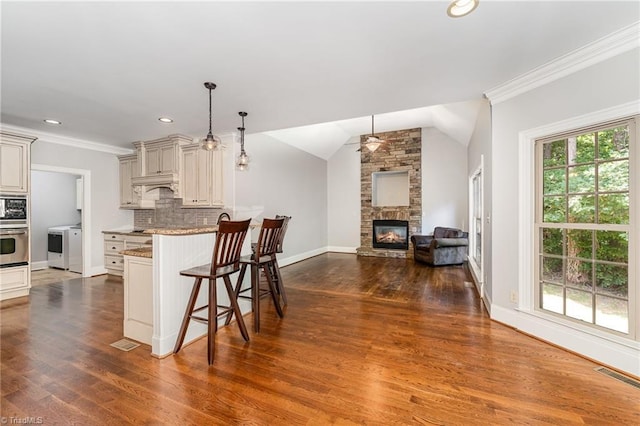 5216 Harley Stafford Dr, Oak Ridge, NC 27310 - kitchen featuring a fireplace, a breakfast bar area, open floor plan, appliances with stainless steel finishes, and ornamental molding
