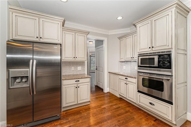 5216 Harley Stafford Dr, Oak Ridge, NC 27310 - kitchen with stainless steel appliances, cream cabinetry, backsplash, light stone counters, and dark wood finished floors