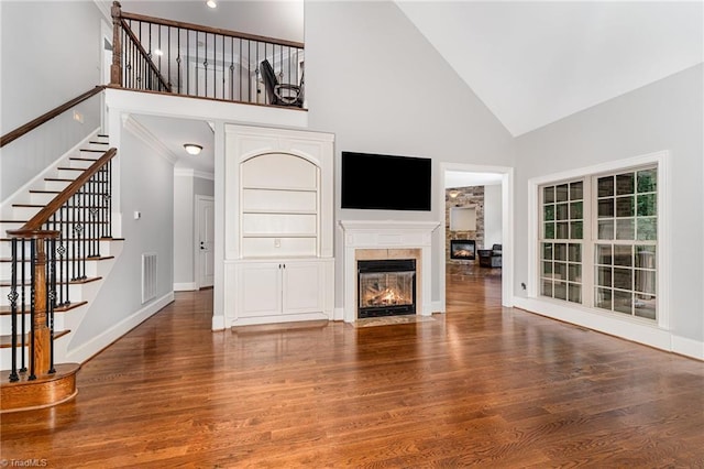 5216 Harley Stafford Dr, Oak Ridge, NC 27310 - unfurnished living room with high vaulted ceiling, wood finished floors, stairway, and a fireplace with flush hearth