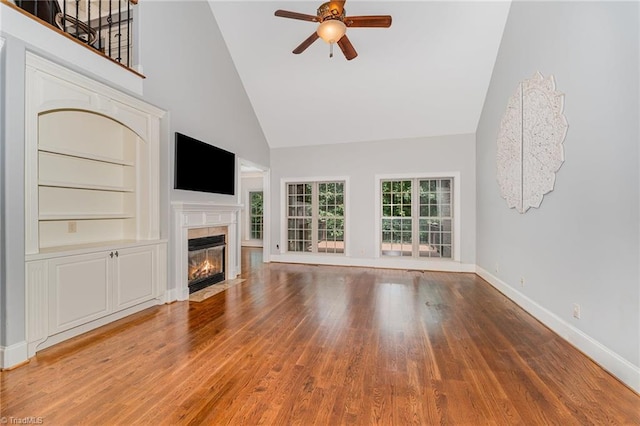 5216 Harley Stafford Dr, Oak Ridge, NC 27310 - unfurnished living room with high vaulted ceiling, a ceiling fan, wood finished floors, a fireplace with flush hearth, and built in shelves