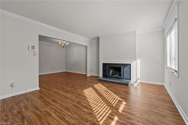 unfurnished living room with hardwood / wood-style floors, a notable chandelier, and crown molding