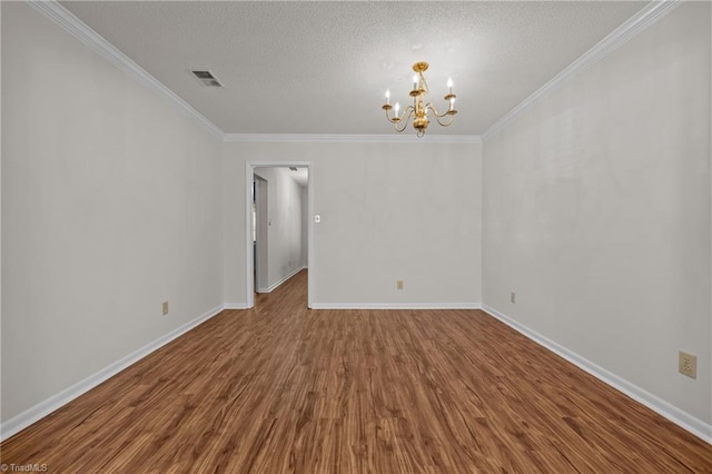 empty room with hardwood / wood-style floors, crown molding, a textured ceiling, and a chandelier