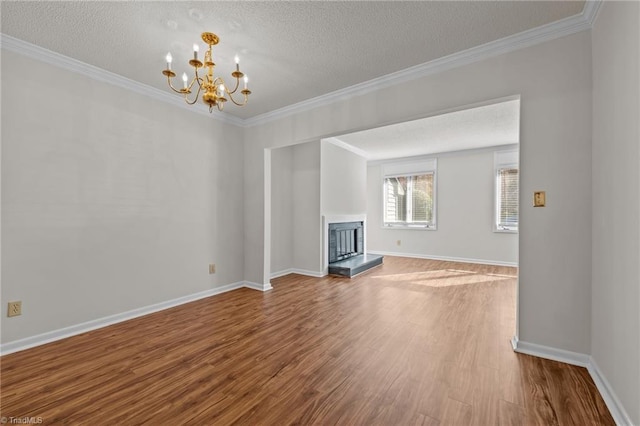 unfurnished living room featuring a chandelier, wood-type flooring, a textured ceiling, and crown molding