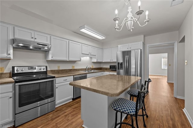 kitchen featuring sink, a kitchen island, hardwood / wood-style floors, white cabinets, and appliances with stainless steel finishes