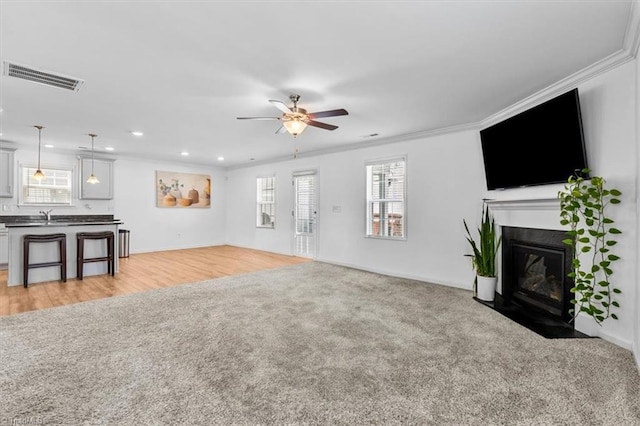 824 Sage Hill Dr, Jamestown, NC 27282 - unfurnished living room featuring ornamental molding, ceiling fan, a fireplace with flush hearth, light colored carpet, and recessed lighting