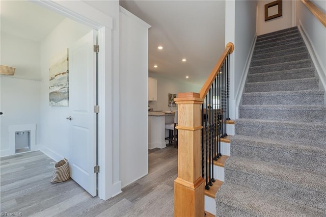 stairway with wood finished floors, recessed lighting, and baseboards