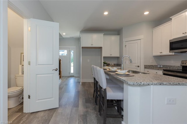 kitchen featuring stainless steel appliances, a sink, white cabinets, dark wood finished floors, and recessed lighting