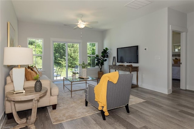 living room with a ceiling fan, wood finished floors, and baseboards