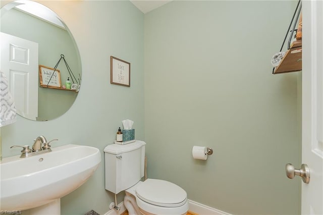 half bath with a sink, toilet, and baseboards