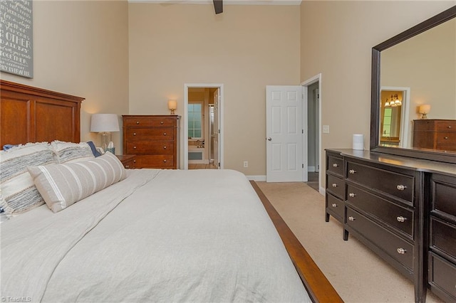 carpeted bedroom with a high ceiling, connected bathroom, and baseboards