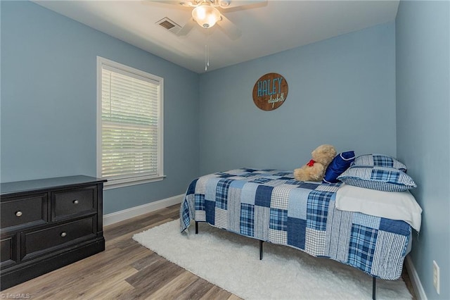 bedroom with ceiling fan, wood finished floors, visible vents, and baseboards