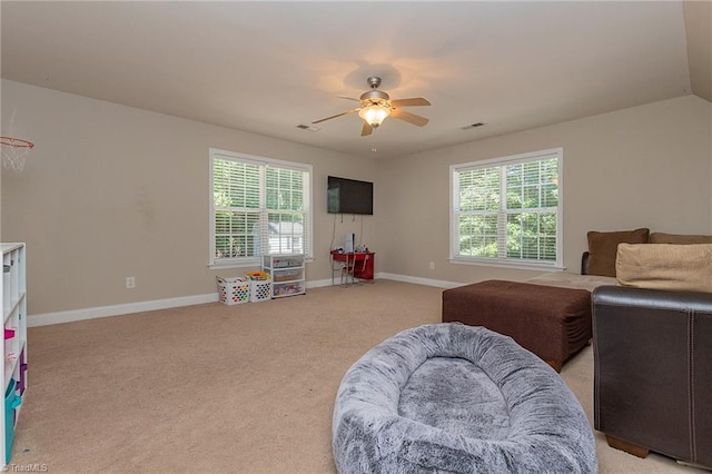 interior space featuring baseboards, multiple windows, a ceiling fan, and light colored carpet