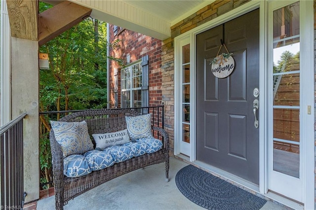 view of exterior entry featuring a porch and brick siding