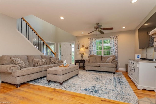 living room with recessed lighting, light wood-style flooring, baseboards, and stairs