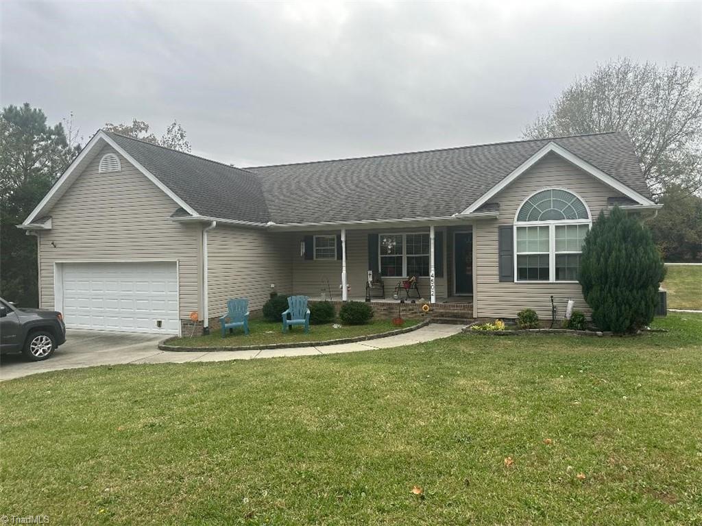 ranch-style house with a garage, a porch, and a front lawn