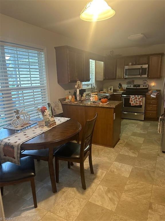 kitchen featuring dark brown cabinets, appliances with stainless steel finishes, and dark stone counters