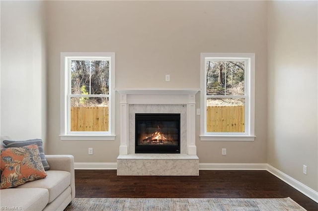 living room with a high end fireplace, a healthy amount of sunlight, and dark hardwood / wood-style flooring