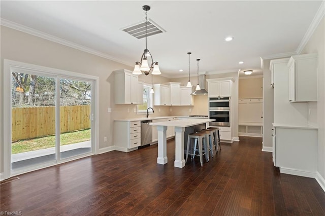 kitchen featuring a center island, white cabinetry, stainless steel appliances, hanging light fixtures, and a breakfast bar area