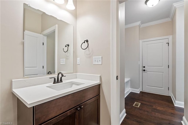 bathroom with wood-type flooring, crown molding, and vanity