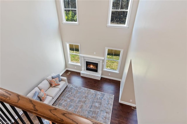 living room with a fireplace, plenty of natural light, dark hardwood / wood-style flooring, and a towering ceiling