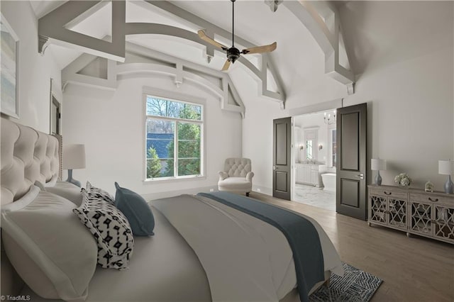 bedroom with ensuite bathroom, hardwood / wood-style floors, and high vaulted ceiling