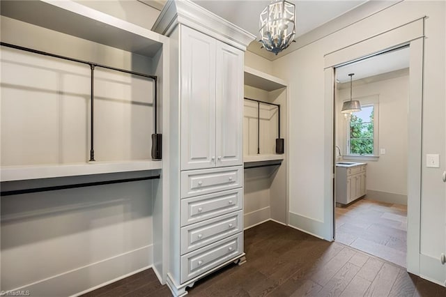 walk in closet featuring dark wood-type flooring, sink, and a chandelier