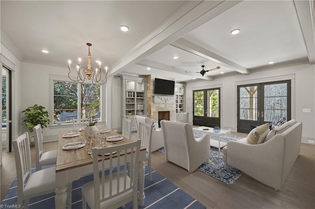 dining room featuring wood-type flooring, a large fireplace, beam ceiling, and french doors