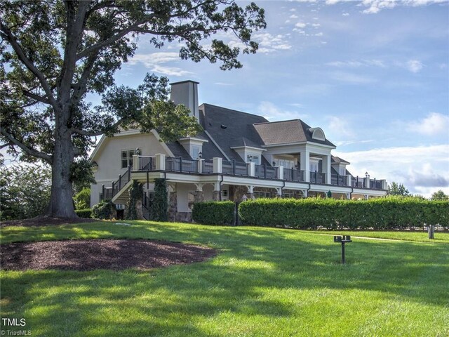 back of house with stairway, a lawn, and stone siding