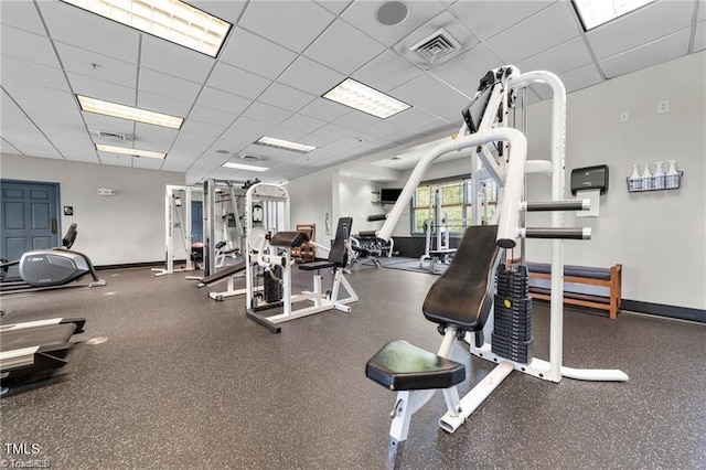 exercise room with visible vents, a paneled ceiling, and baseboards