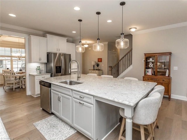 kitchen featuring a sink, appliances with stainless steel finishes, light wood-style flooring, and crown molding