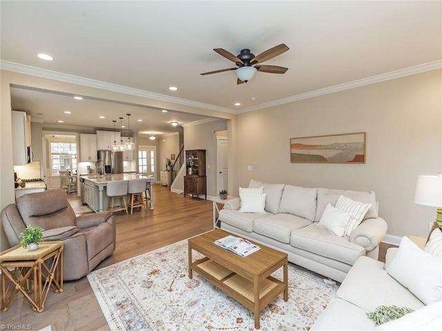 living area with light wood-type flooring, ornamental molding, a ceiling fan, recessed lighting, and baseboards