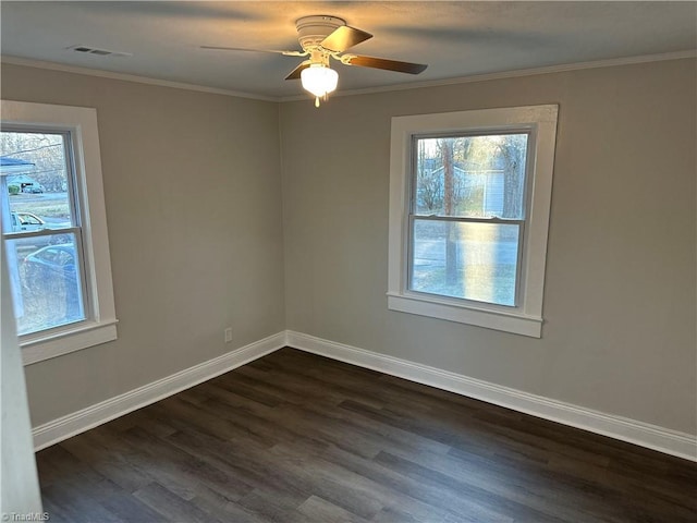 spare room featuring ornamental molding, visible vents, plenty of natural light, and dark wood-style floors