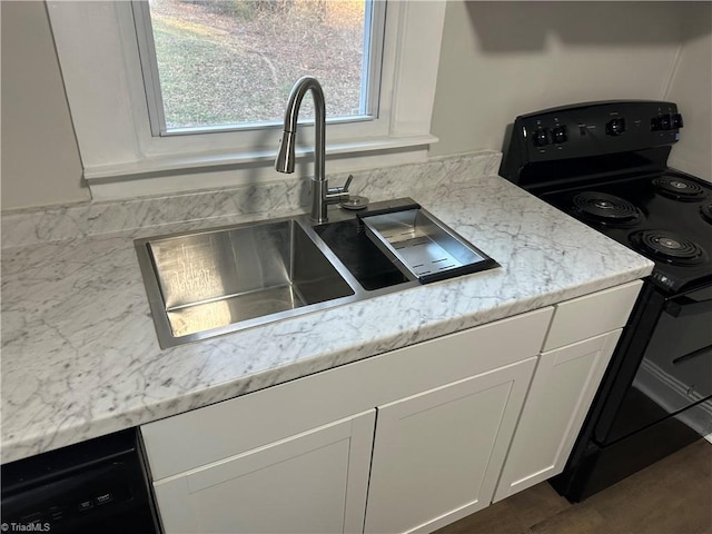 kitchen featuring black appliances, a sink, white cabinetry, and light stone countertops