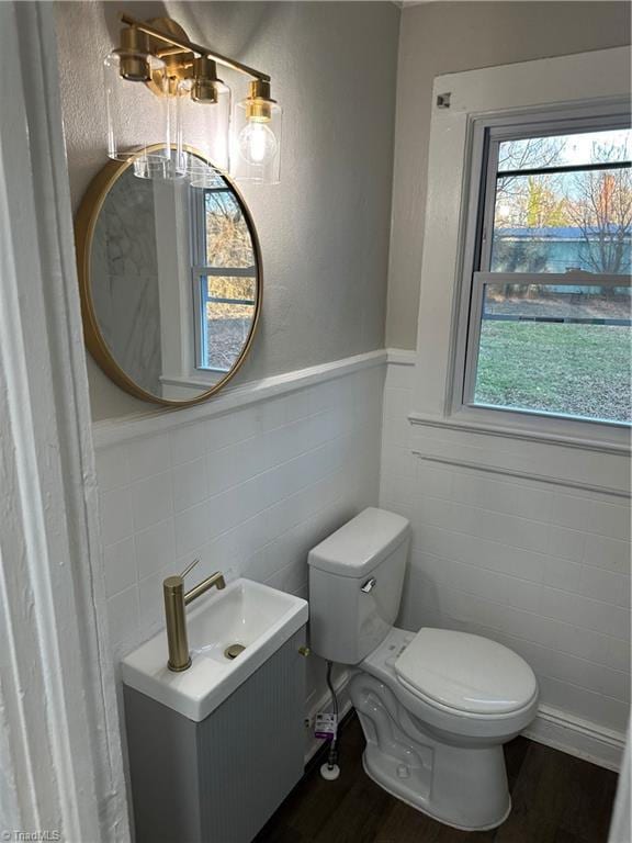 half bath with vanity, wainscoting, wood finished floors, and toilet