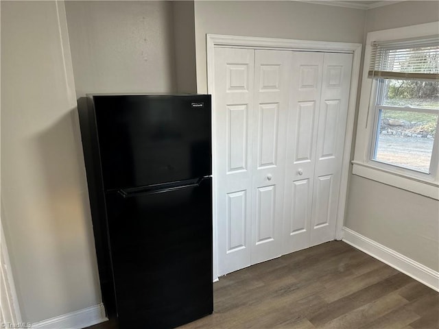 interior space with a closet, baseboards, dark wood-style flooring, and freestanding refrigerator