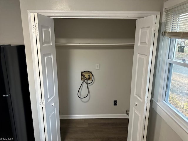 clothes washing area with dark wood-style flooring, washer hookup, laundry area, and baseboards