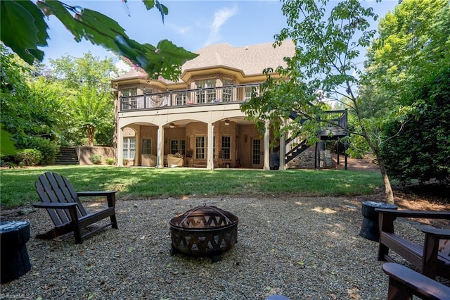 back of house featuring a yard, a deck, and an outdoor fire pit