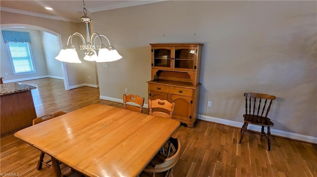 dining room with hardwood / wood-style floors, ornamental molding, and an inviting chandelier