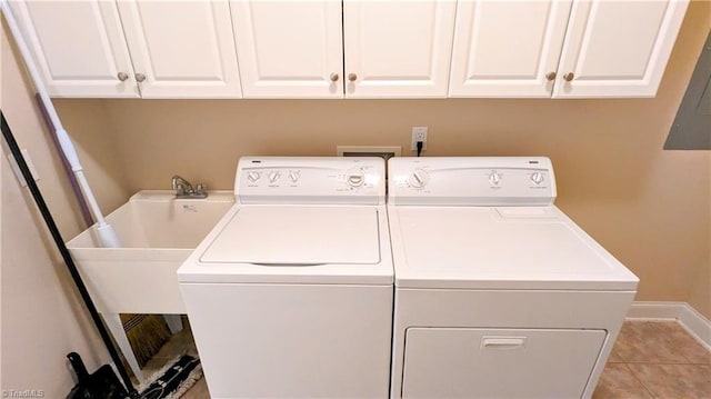 laundry room with cabinets, washing machine and dryer, light tile patterned floors, and electric panel