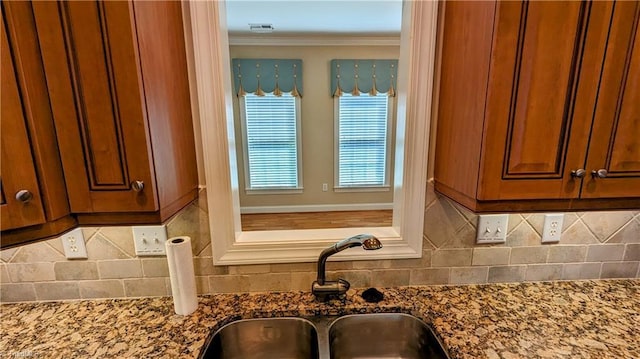 room details featuring decorative backsplash, stone countertops, crown molding, and sink