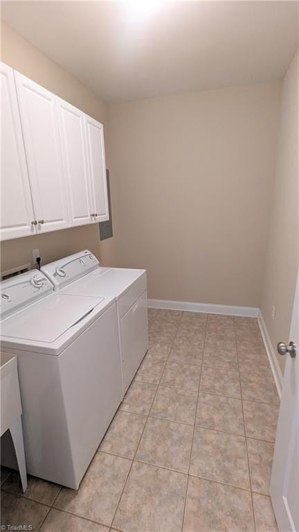 clothes washing area with cabinets, light tile patterned floors, and washing machine and dryer