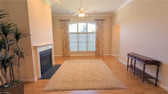 living room with ceiling fan, light wood-type flooring, and crown molding