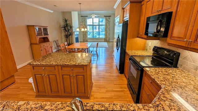 kitchen with pendant lighting, a center island, black appliances, crown molding, and tasteful backsplash